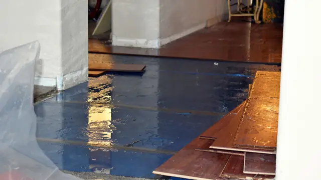 Wood floor boards pulled up over blue protective sheeting